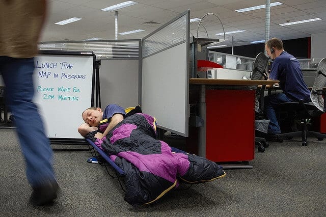 man napping at work in sleeping bag